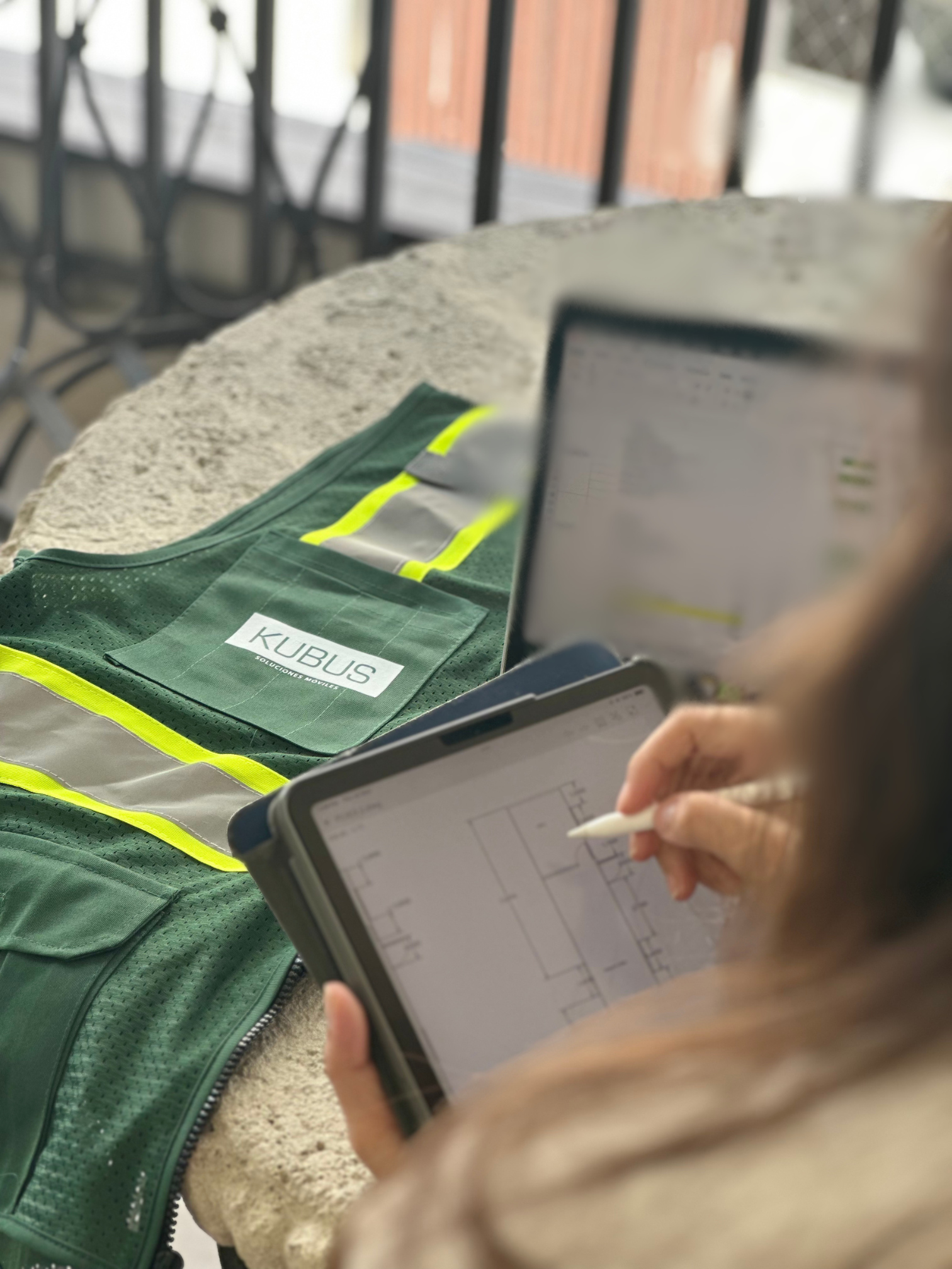 Profesional Kubus revisando planos en tablet junto al chaleco de la marca